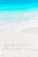 Dream written on sandy beach with soft ocean wave on background photo
