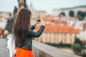 Young woman taking selfie on smartphone on Charles Bridge in Prague, photo
