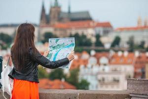 mujer joven feliz con un mapa de la ciudad en la ciudad. viaje mujer turista con mapa al aire libre durante las vacaciones en europa. foto