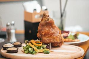Roasted pork knuckle eisbein with salad and mustard on wooden cutting board photo