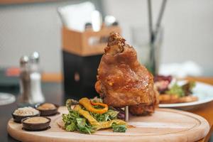 Roasted pork knuckle eisbein with salad and mustard on wooden cutting board photo