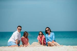 Family of four making sand castle at tropical white beach photo