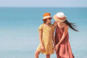 Beautiful mother and daughter at the beach enjoying summer vacation photo