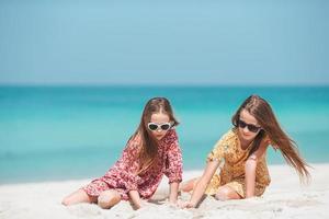 Little happy funny girls have a lot of fun at tropical beach playing together photo