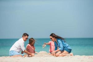 Family of four making sand castle at tropical white beach photo