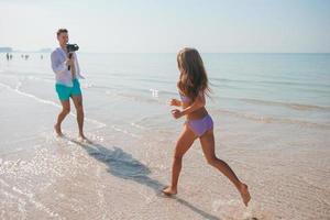 Little girl and happy dad having fun during beach vacation photo