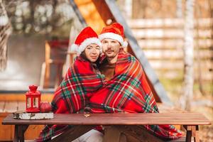 Young family in santa hat sitting on the wooden old table background of their house photo