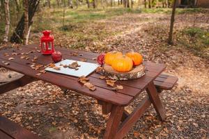 Orange pumpkin and leaves near laptop computer on a table. Autumn season time photo