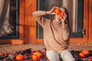 Beautiful girl covered her eyes with pumpkins at autumn warm day