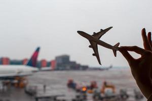Closeup mano sosteniendo un modelo de avión en el aeropuerto foto