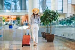 mujer joven con sombrero con equipaje en el aeropuerto internacional. foto