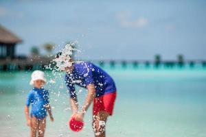 Little girl and happy dad having fun during beach vacation photo