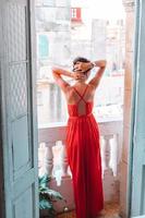 Young attractive woman in red dress on old balcony in apartment in Havana photo