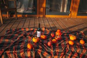 Pumpkins and bottle of red wine with two glasses on the blanket photo