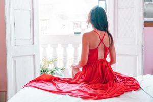 Young attractive woman in red dress on old balcony in apartment in Havana photo