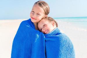niñas divirtiéndose corriendo con una toalla y disfrutando de las vacaciones en una playa tropical con arena blanca y agua turquesa del océano foto