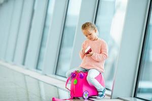 Adorable little girl in airport with her luggage waiting for boarding photo