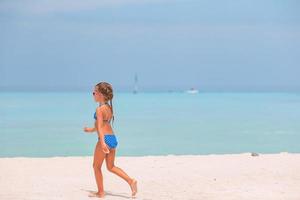 Beautiful little girl in dress at beach having fun. Funny girl enjoy summer vacation. photo