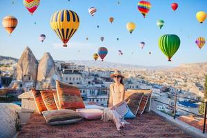 mujer joven feliz durante el amanecer viendo globos aerostáticos en capadocia, turquía foto