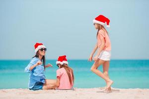 Adorable little girls and young mother on tropical white beach photo