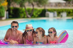 Happy family of four in swimming pool photo