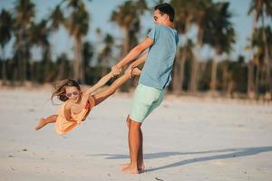 Little girl and happy dad having fun during beach vacation photo