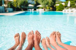 Cerca de las piernas de cuatro personas al lado de la piscina foto