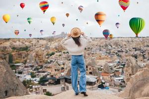 mujer joven feliz durante el amanecer viendo globos aerostáticos en capadocia, turquía foto