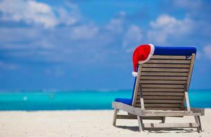 Red santa hat on chair longue at tropical white beach photo