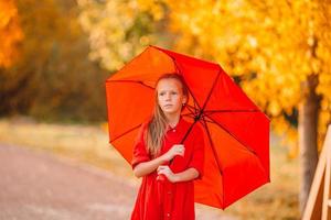 Happy child girl laughs under red umbrella photo