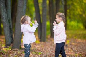 niñas adorables jugando en el hermoso parque de otoño al aire libre foto