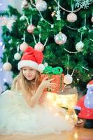 Little cute girl near christmas tree. Children under Christmas tree with gift boxes. photo