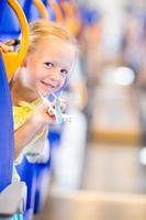 Adorable little girl traveling on train and having fun with airplane model in hands photo