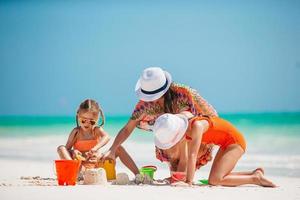 Family of four making sand castle at tropical white beach photo