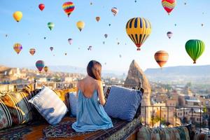 Happy young woman during sunrise watching hot air balloons in Cappadocia, Turkey photo