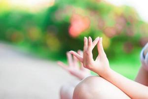 Fitness young woman meditating in the park. Female fitness model training outside in the park. Healthy wellness fitness lifestyle. photo