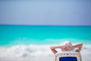 Young woman in hat on a tropical beach looking on the beautiful sea photo