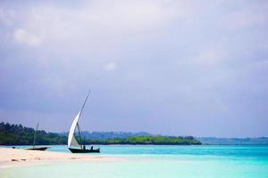 Old wooden dhow on white beach in the Indian Ocean