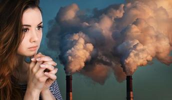 praying woman against of pipes polluting an atmosphere photo