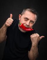 elderly man with red pepper in his mouth photo