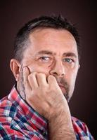 thoughtful elderly man with hand near the face photo