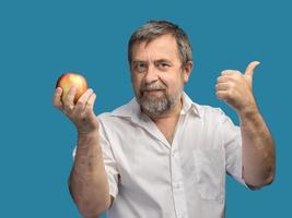 hombre de mediana edad sonriente sosteniendo una manzana roja foto
