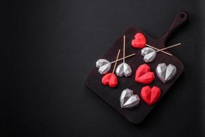 Delicious sweet heart shaped chocolate candies on a dark concrete background photo