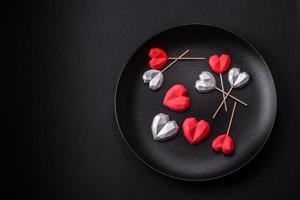 Delicious sweet heart shaped chocolate candies on a dark concrete background photo