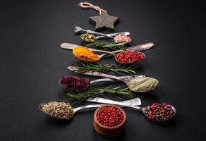 Composition consisting of a variation of spices in metal spoons laid out in the shape of a Christmas tree photo