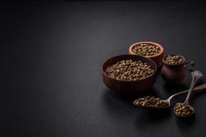 Spice, allspice green in a wooden bowl on a black concrete background photo