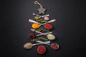 Composition consisting of a variation of spices in metal spoons laid out in the shape of a Christmas tree photo