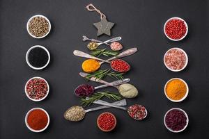 Composition consisting of a variation of spices in metal spoons laid out in the shape of a Christmas tree photo