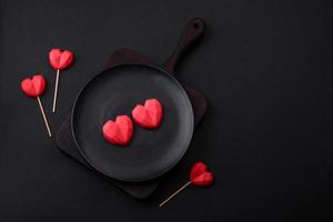 Delicious sweet heart shaped chocolate candies on a dark concrete background photo