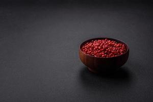 Spice, allspice peas of red or pink color in a wooden bowl photo